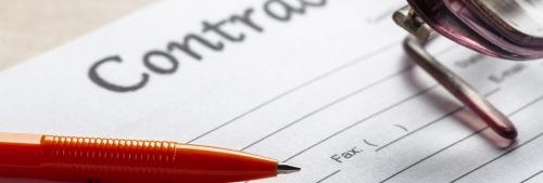 A contract document lays on a table near a pen and a pair of glasses, ready for signing.
